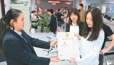 河北省承德市網(wǎng)絡(luò)代購經(jīng)營者陳晨(右)從工作人員手中接過帶有統(tǒng)一社會(huì)信用代碼的營業(yè)執(zhí)照。 劉環(huán)宇攝(人民圖片)